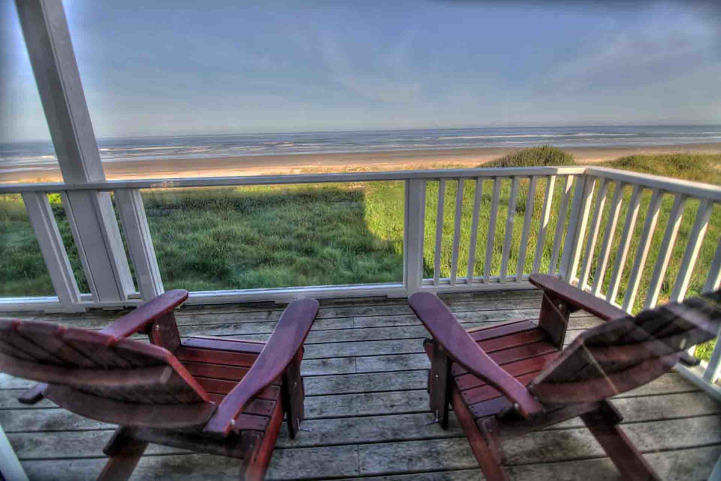 A large ocean front deck overlooking an expansive, sandy beach.