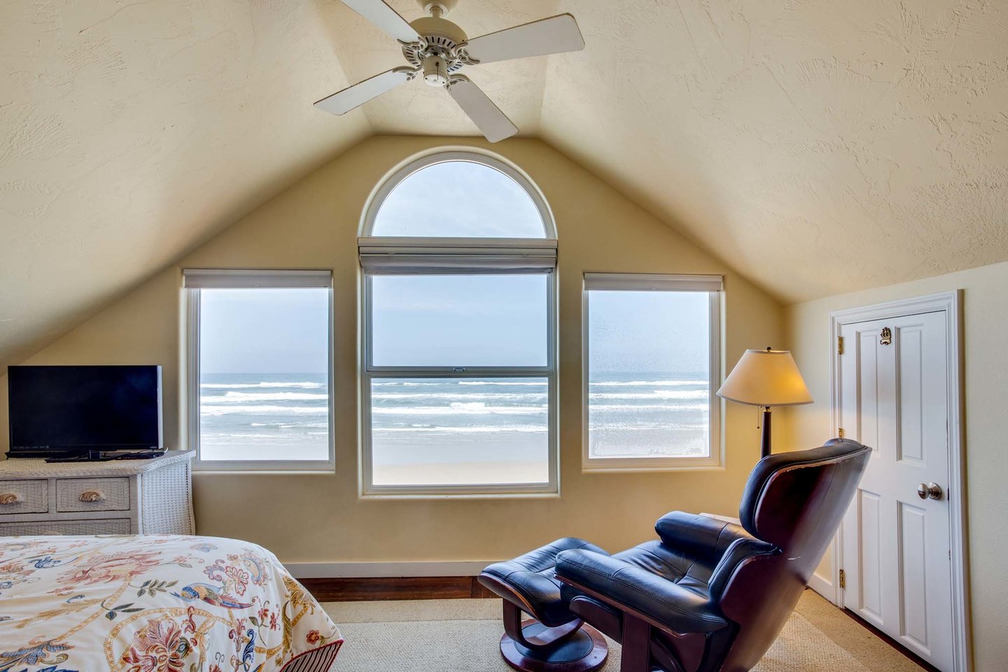 Relax in the primary bedroom with ocean views and  comfy chair.