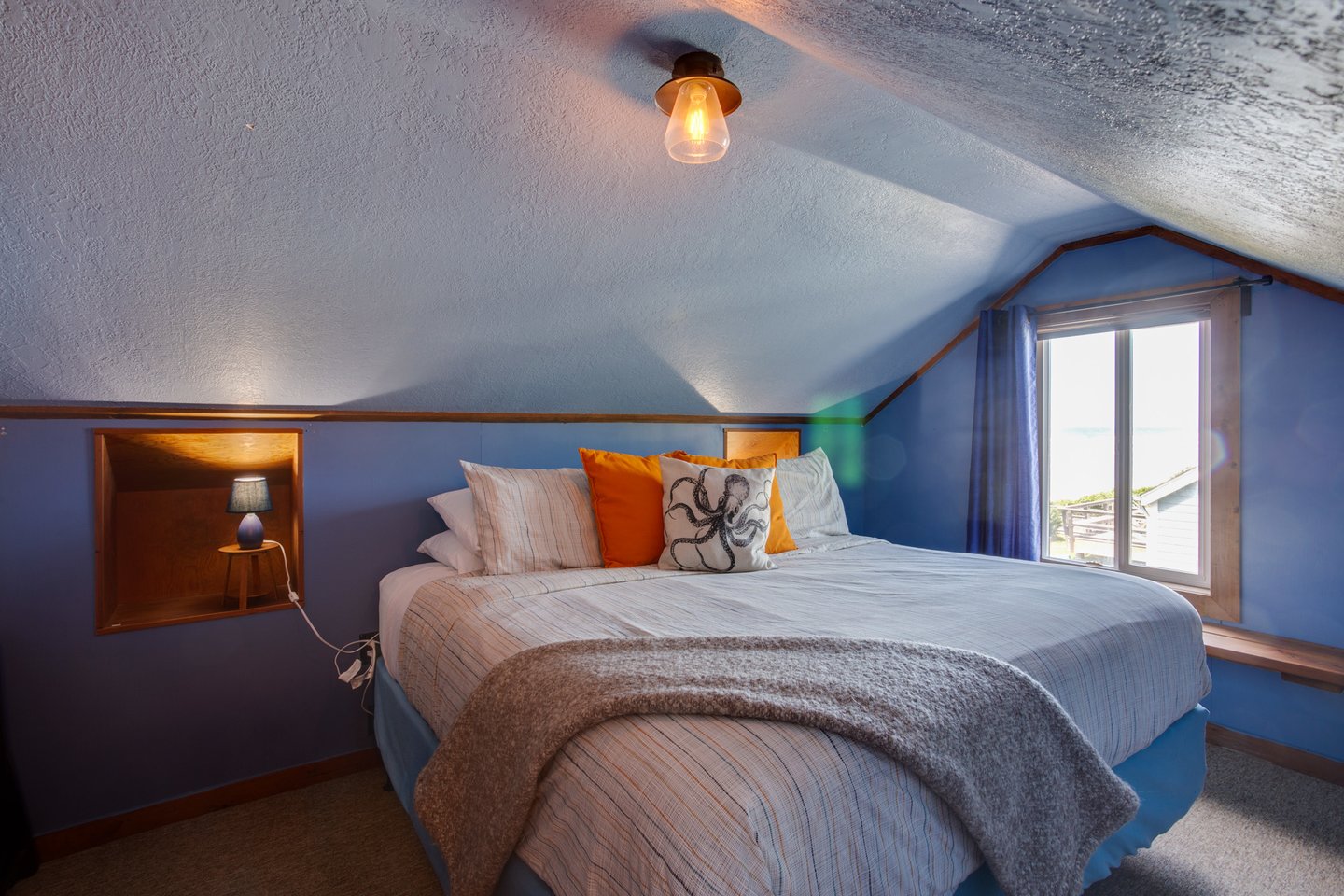 This king bed has a view of the ocean right out the window.