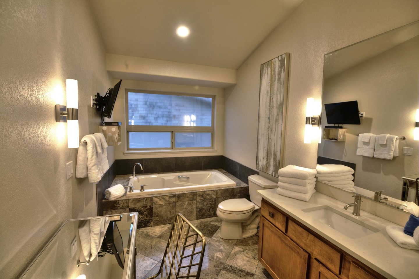 The Primary Bath is steeped in luxury with double vanity, tiled walk in shower, soaking tub and TV.