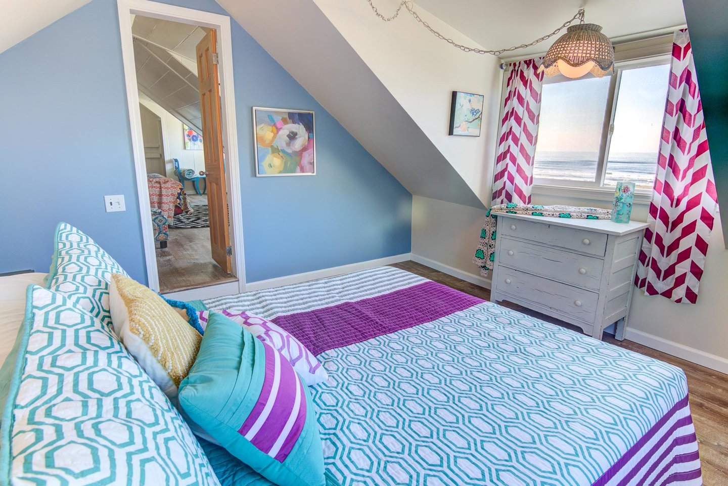 This bright and colorful bedroom at the top of the stairs has an ocean view.