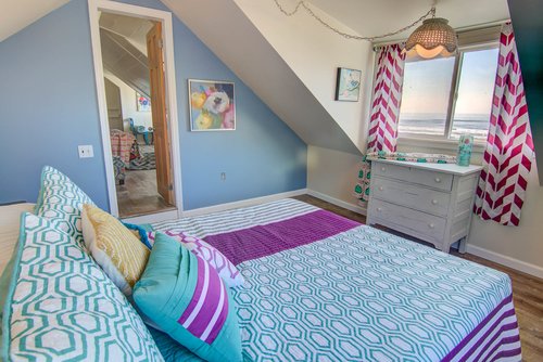 This bright and colorful bedroom at the top of the stairs has an ocean view.