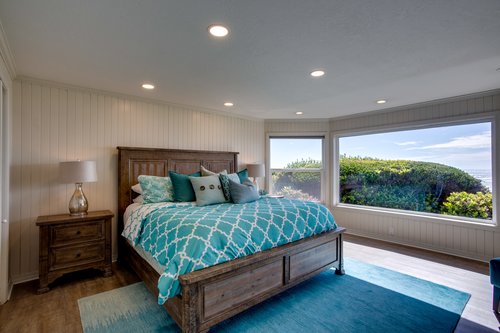 Large primary bedroom with ocean views and television.