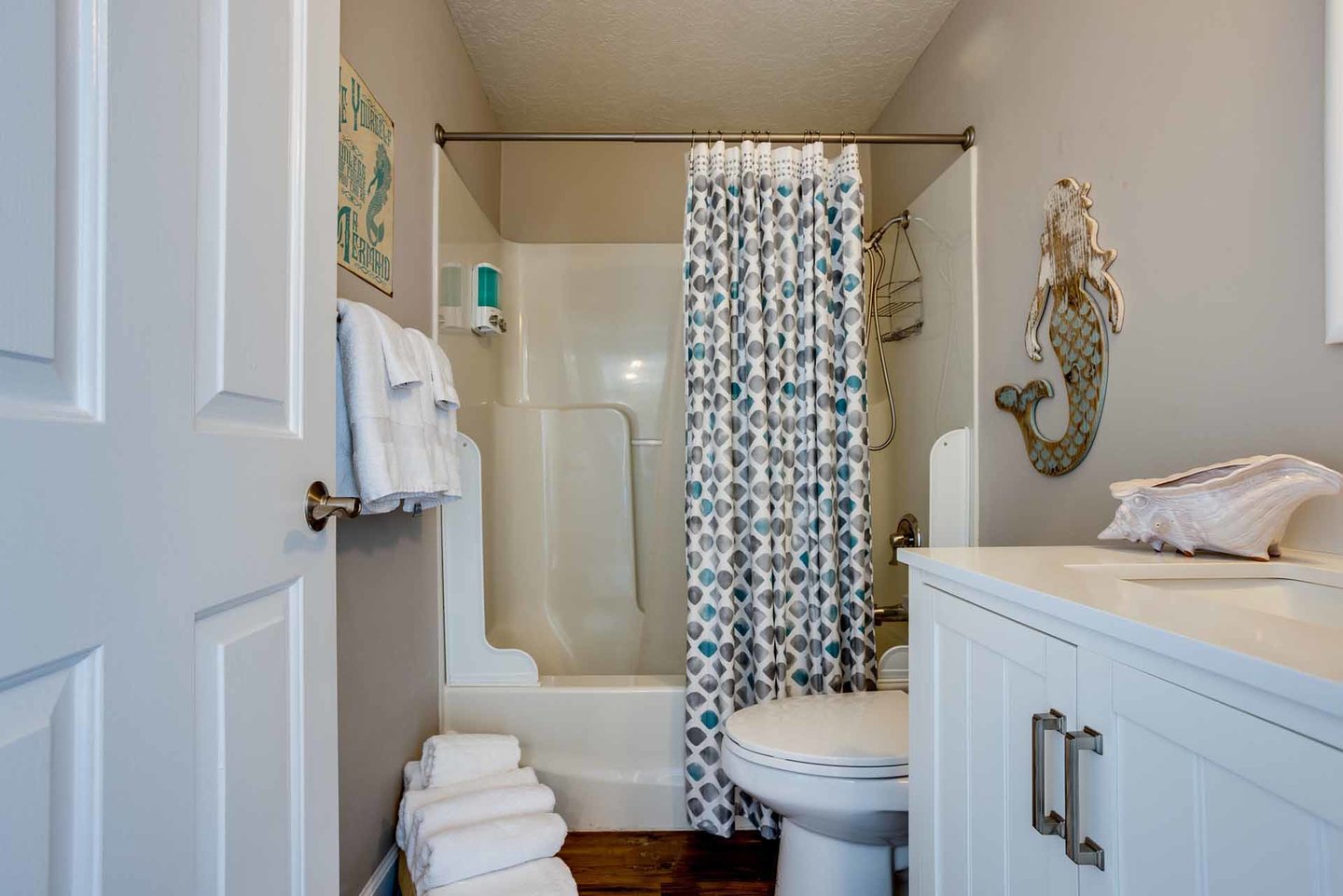 The bath in the hallway with a tub/shower enclosure.