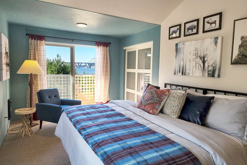 Open the sliding doors to a balcony with Alsea Bay Bridge views.