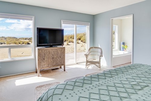 Coastal views, access to the deck, and ensuite bath in the primary bedroom.